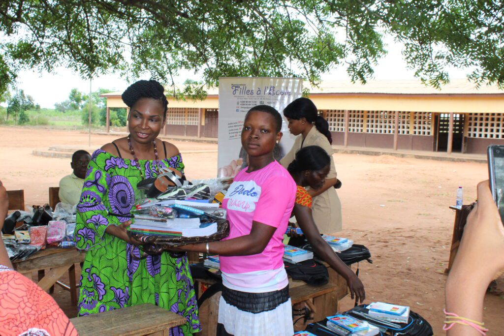 La Présidente de Filles à l'Ecole  (FE) Togo remet un kit scolaire à une bénéficiaire. 