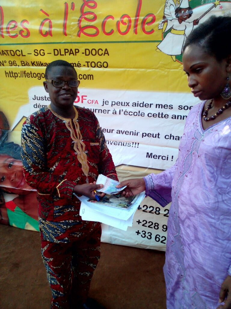 La Présidente de Filles à l'Ecole (FE) Togo remettant les frais d'écolage au Directeur du CEG Soko Tomety en 2017